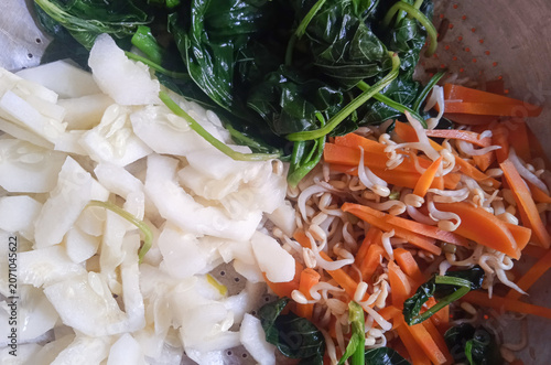 cooked spinach, carrots, cucumber, and bean sprouts for pecel, a traditional Javanese dish, on a plate photographed from above.