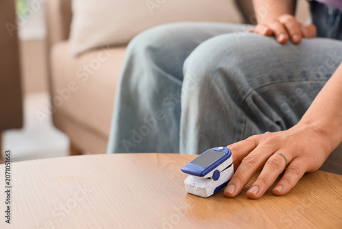 Foto Person measuring oxygen saturation with fingertip pulse oximeter at home