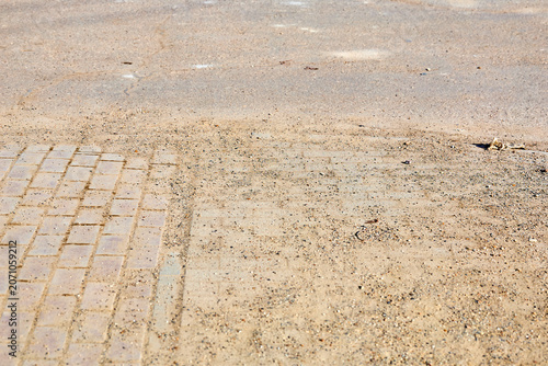 Fotografie Sandy dirt road with brick edge transition on sunny day, the consequences of a d