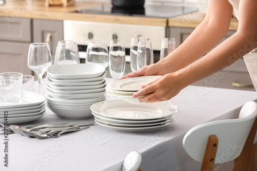Photos Person setting a table with white dishes and glassware