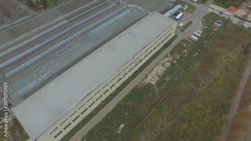 Drone flying forward over factory roof with downward rotation
