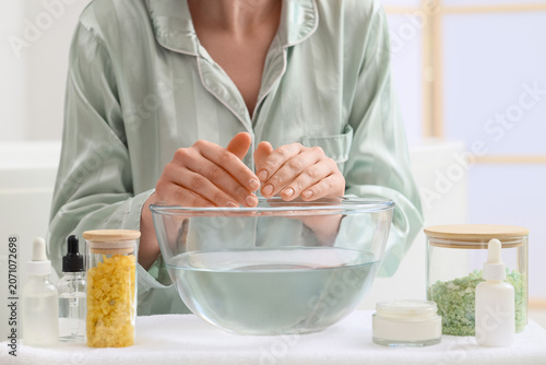 Foto Person soaking hands in bowl of water with spa products
