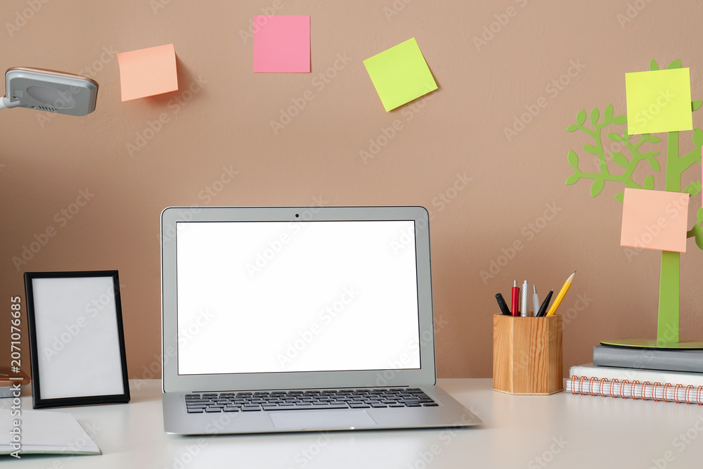 Fototapeta premium Minimalist workspace with laptop and sticky notes on wall