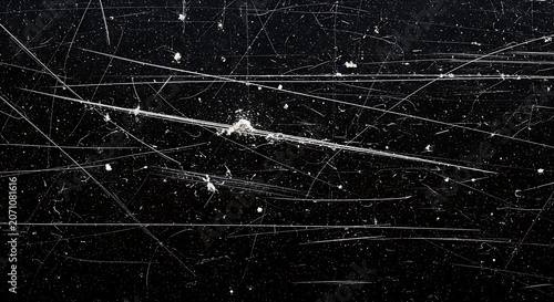 Textured pattern of many white scratches and dust specks on a dark black surface