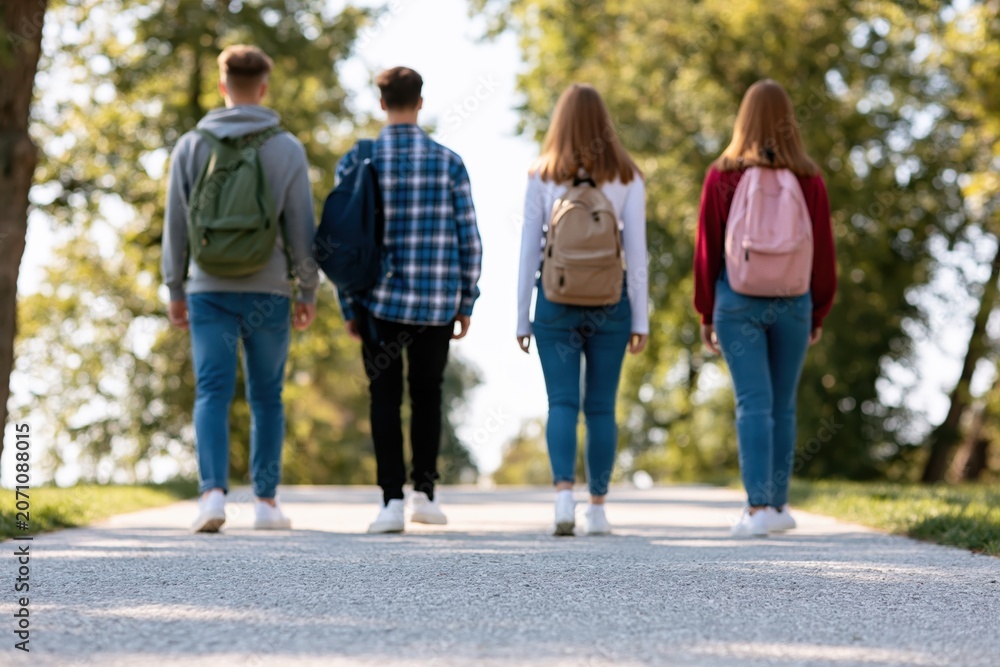 Obraz premium Students and teenagers walking with backpacks on a scenic park path at university
