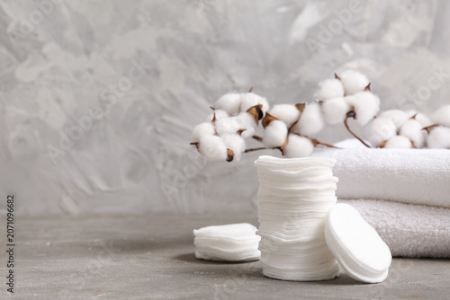 Fotografia Stack of cosmetic pads, clean towels and cotton branch on grunge background