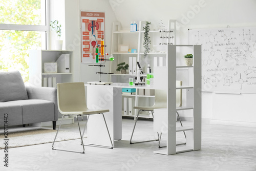 Interior of laboratory with workplace, shelf units and chemical glassware