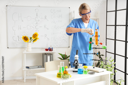Happy female scientist with flasks of samples, sunflower seeds and sprouts wo...