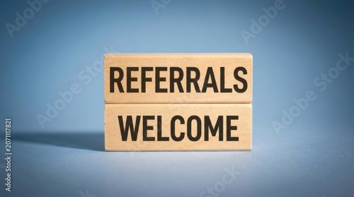 Wooden blocks with 'referrals welcome' message on blue background