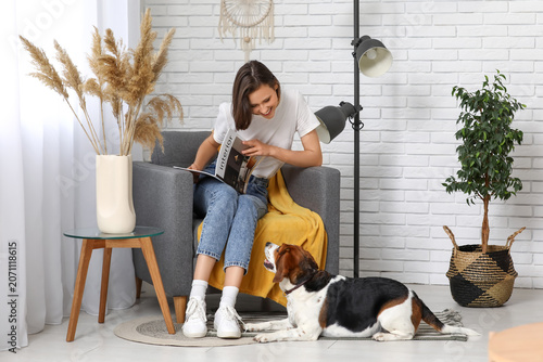 Young woman reading book and adorable Beagle dog lying on floor at home
