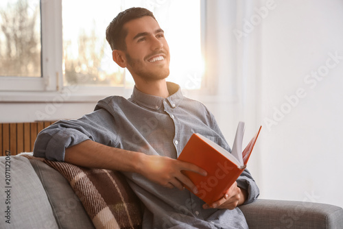 Young man reading book on s...