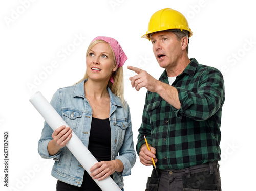 Professional construction contractor and female architect discussing blueprints, male builder in hard hat pointing at project site, industrial team collaboration