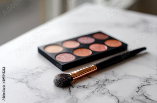Warm-toned blush palette and makeup brush artfully arranged on a marble surface.