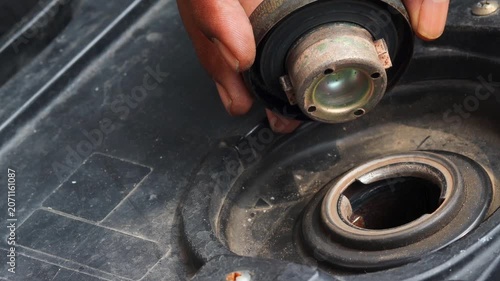 Person checking fuel level by opening a motorcycle fuel tank. Close up of vehicle inspection, transportation preparation, and motorcycle maintenance.
