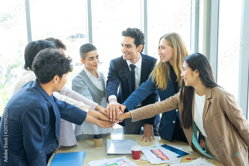 Group of business people joining hands together in office. Teamwork concept.