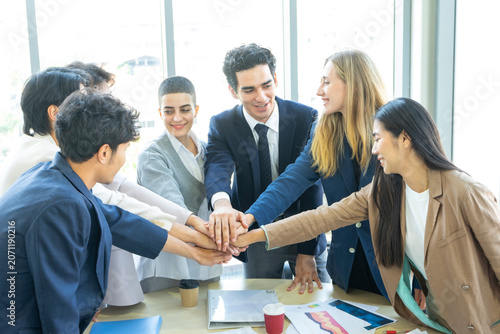 Group of business people joining hands together in office. Teamwork concept.