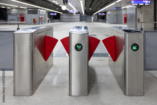 Empty subway station featuring stainless steel turnstiles with green indicators