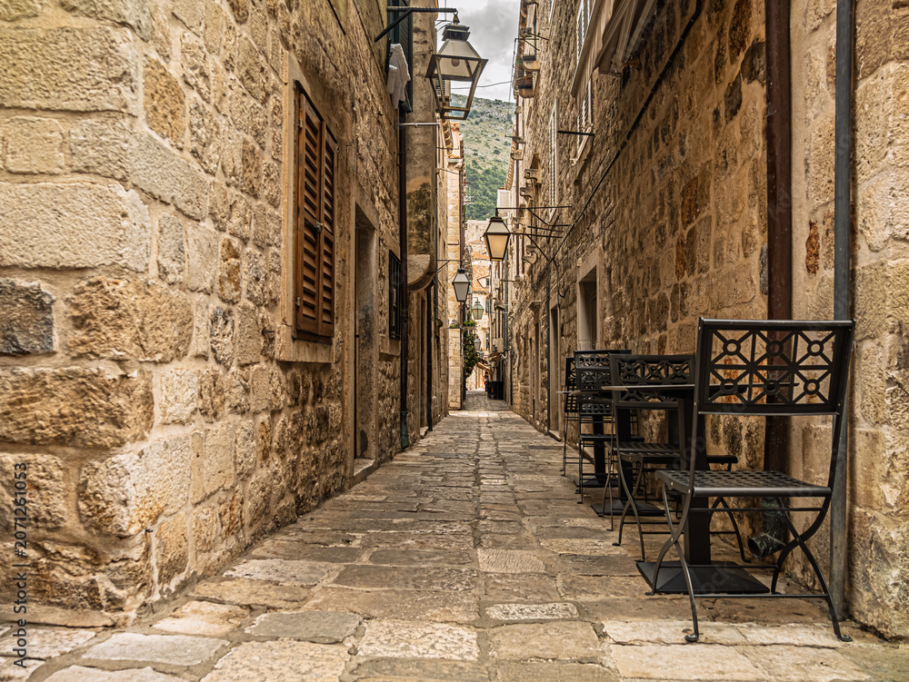 Fototapeta premium Narrow Medieval Stone Alley With Tables And Chairs