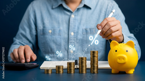 Person points at increasing stacks of coins showing percentage growth next to a yellow piggy bank on a desk as part of a financial savings strategy
