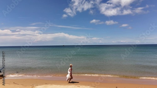 Woman jogging along the shoreline on a sunny day at a tropical beach