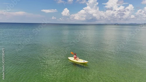Young woman kayaking on clear green water during a sunny day