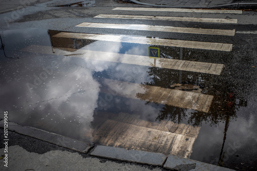 A puddle on an empty zebra crossing on a summer day