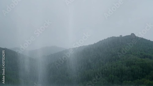 The video captures a scenic view of a mountainous landscape during rainy weather