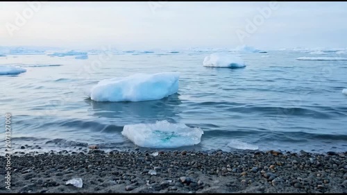The video showcases a serene coastal scene with ice chunks floating on calm, icy waters