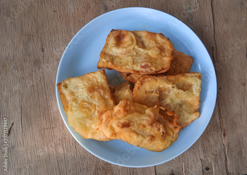 battered and fried tempe gembus served on a blue plastic plate on a wooden table