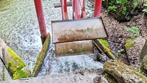 Historic water mill sluice gate channels a fast flowing stream through a lush natural setting. Rushing water, rustic engineering, and tranquil countryside create a timeless scene