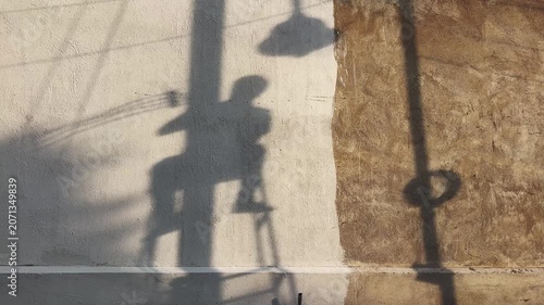 Silhouette shadow of a utility worker seated on an electrical pole while performing maintenance work, highlighting infrastructure services, skilled labor and urban utility operations