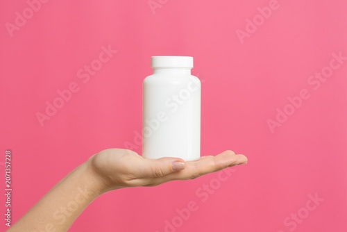 Hand holding white blank medicine bottle, wellness concept