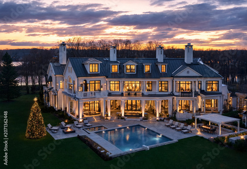 Luxurious mansion with holographic security interface features warm evening lighting by pool and garden