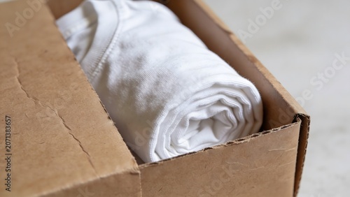 White rolled shirt inside a brown cardboard shipping box for eco-friendly delivery