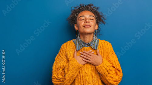 Woman with eyes closed and hands clasped to heart in a moment of gratitude