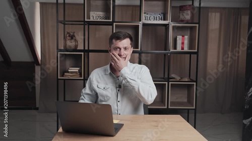 Man shows someone a peace sign with his fingers, turns to the camera and prepares to go on the air. Person is sitting at a table with a laptop. Interview or educational channel.