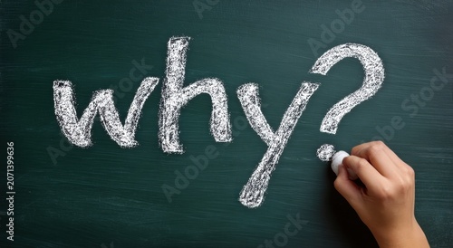 Hand writing why? in white chalk on a dark green chalkboard