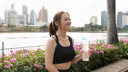 Foto Smiling Thai Woman Holding Water Bottle in Benjakitti Park Bangkok