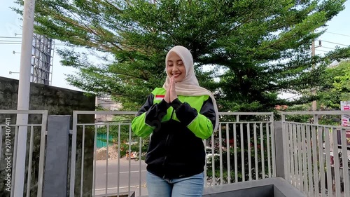 A young Muslim Asian woman, an online motorcycle taxi driver, is doing her job.