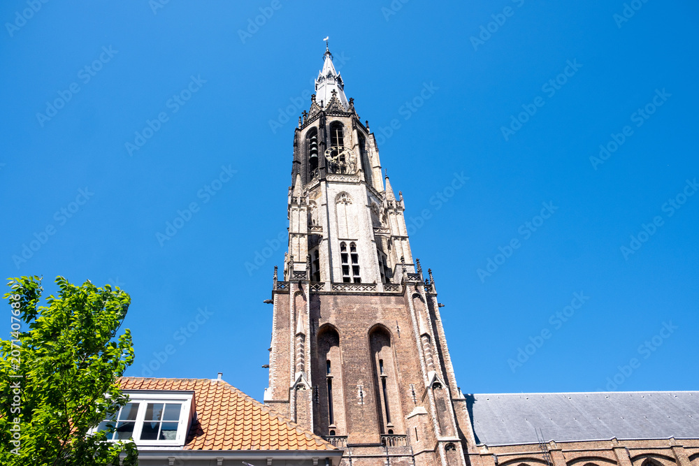 Obraz premium Nieuwe Kerk New Church Gothic tower above Delft city center under blue sky, Netherlands