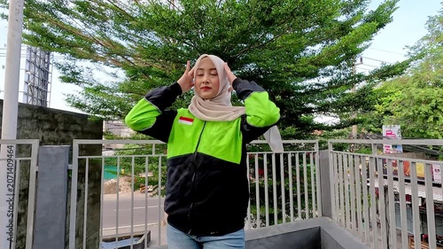 A young Muslim Asian woman, an online motorcycle taxi driver, is doing her job.