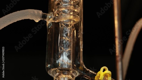 Gin Distillation Alcohol Clear Liquid Flowing Through Glass Tube Into Beaker Laboratory Equipment Close Up Transparent Scientific Process Industrial Precise Clean Glass Coil Condenser Distillation