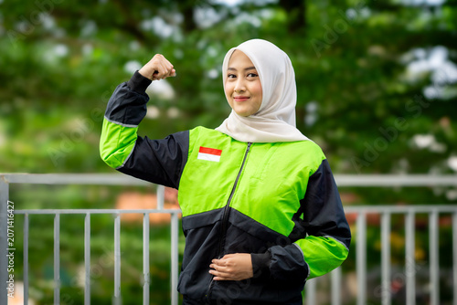 A young Muslim Asian woman, an online motorcycle taxi driver, is doing her job.