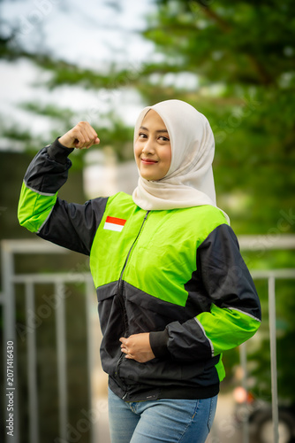 A young Muslim Asian woman, an online motorcycle taxi driver, is doing her job.