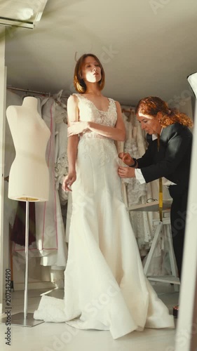 Fashion designer taking measurements of bride in wedding dress