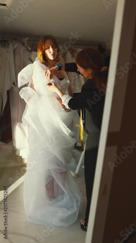Fashion designer assisting a bride with wedding dress fitting