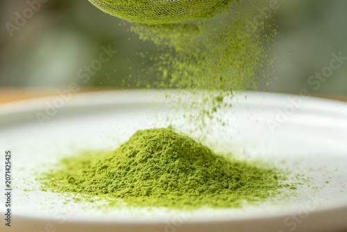matcha. Sifted green matcha tea powder falling onto a white ceramic surface. organic drinks, culinary recipes, designed for green tea packaging and cafe menus.