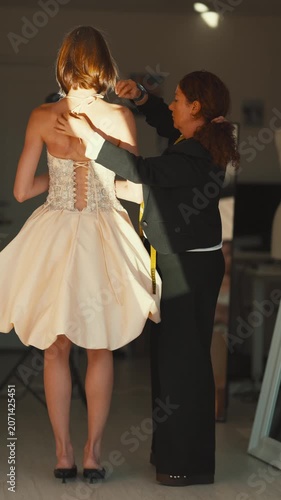 Fashion designer assisting a model with wedding dress fitting