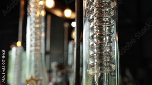 Distillation column glass coil laboratory equipment for alcohol production and gin distillation, industrial transparent scientific apparatus with close up reflective surface, modern chemistry
