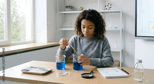 STEM chemistry class. Teenage girl student doing chemical experiment with glass flasks photo